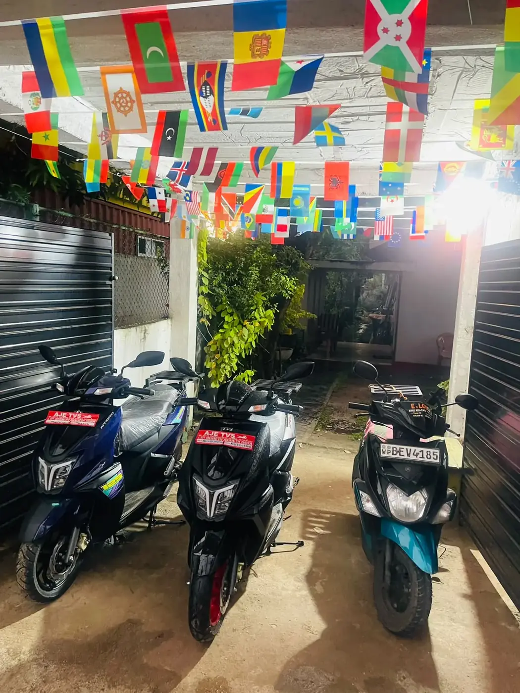 TVS Ntorq and Yamaha Ray ZR scooters lined up under flags at CeylonGoBikes