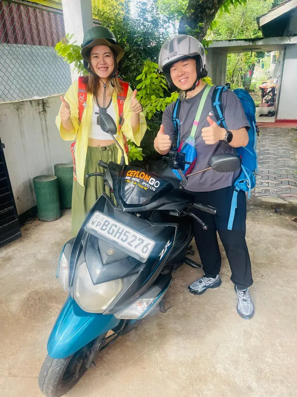 Travellers giving thumbs up beside a CeylonGo Yamaha Ray ZR scooter