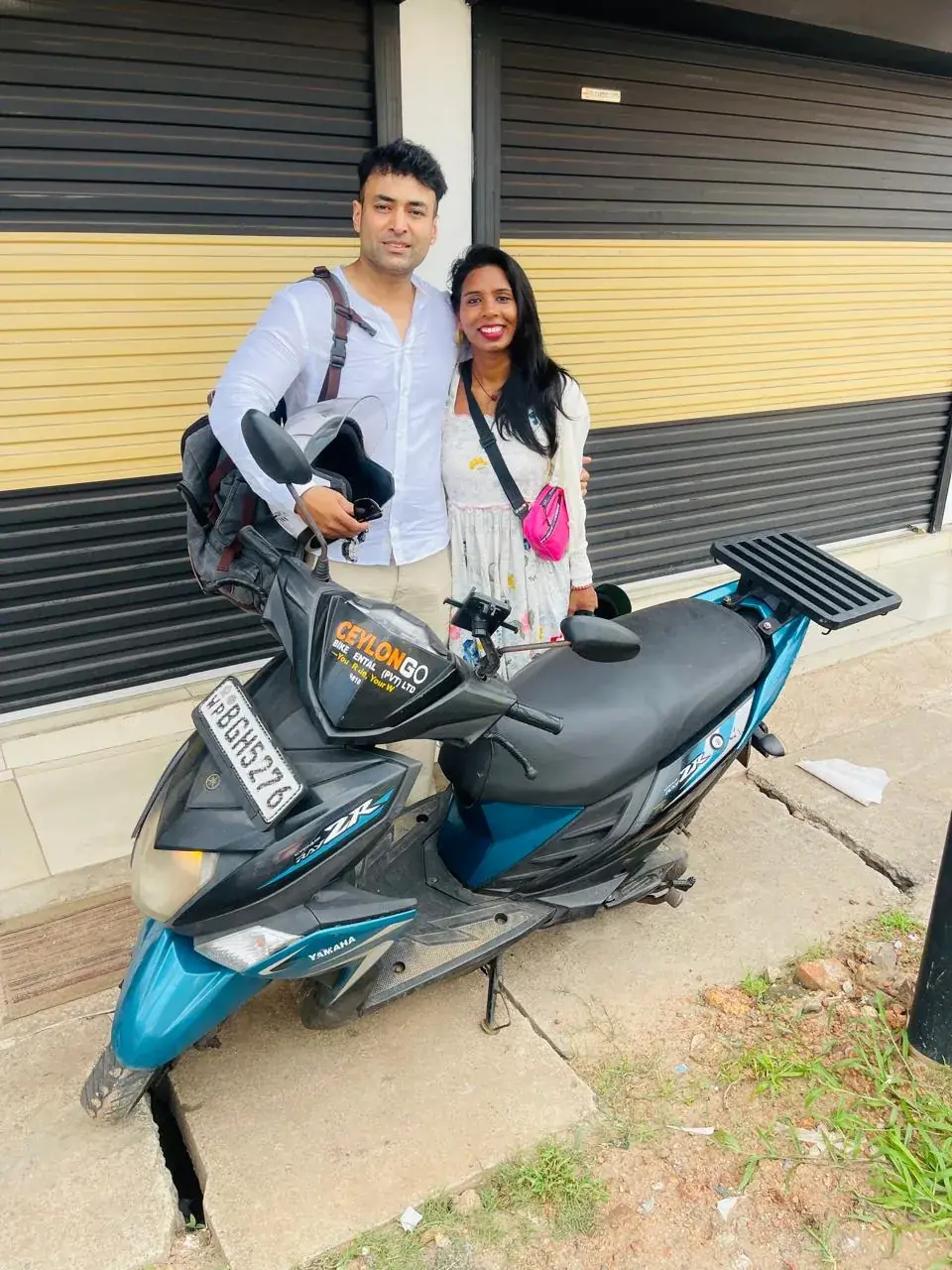 Couple posing behind a teal CeylonGo Yamaha Ray ZR scooter