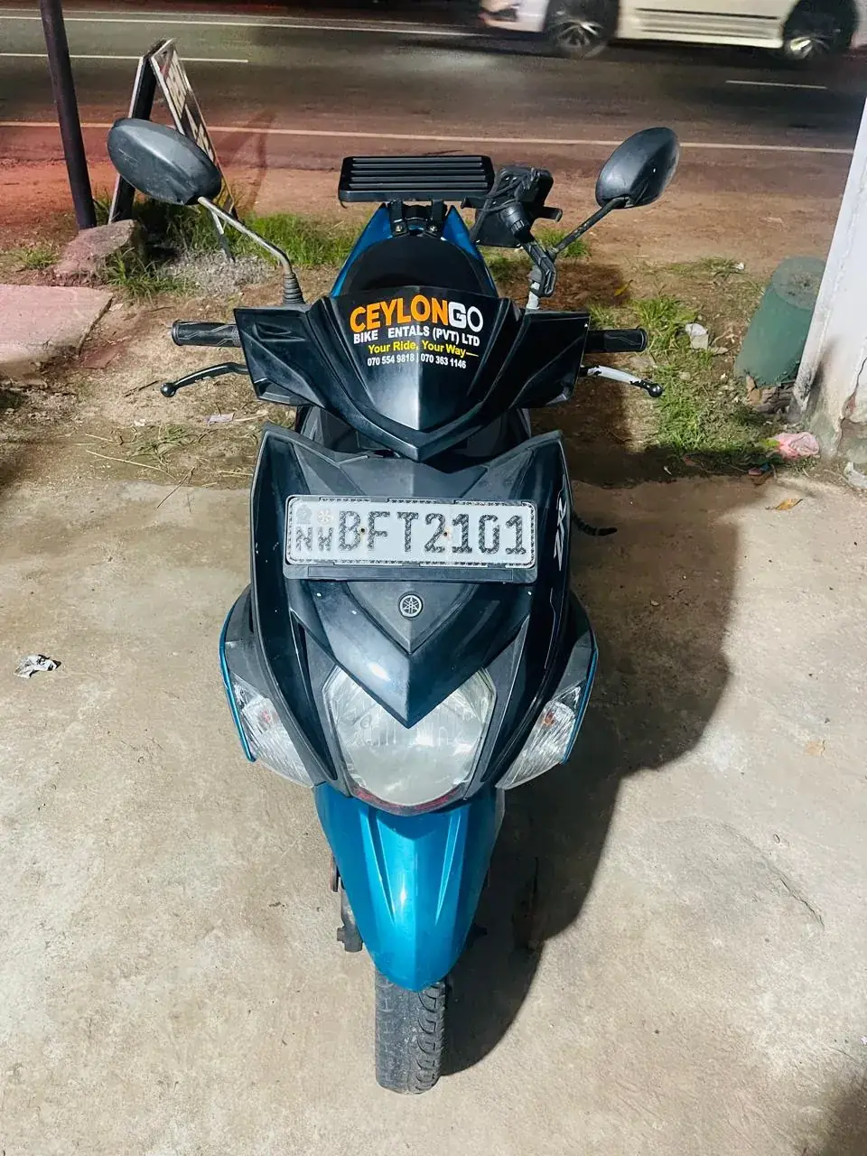 Front view of a CeylonGo branded Yamaha Ray ZR scooter at night