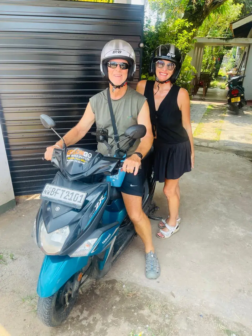 Couple with helmets and a teal CeylonGo Yamaha Ray ZR scooter