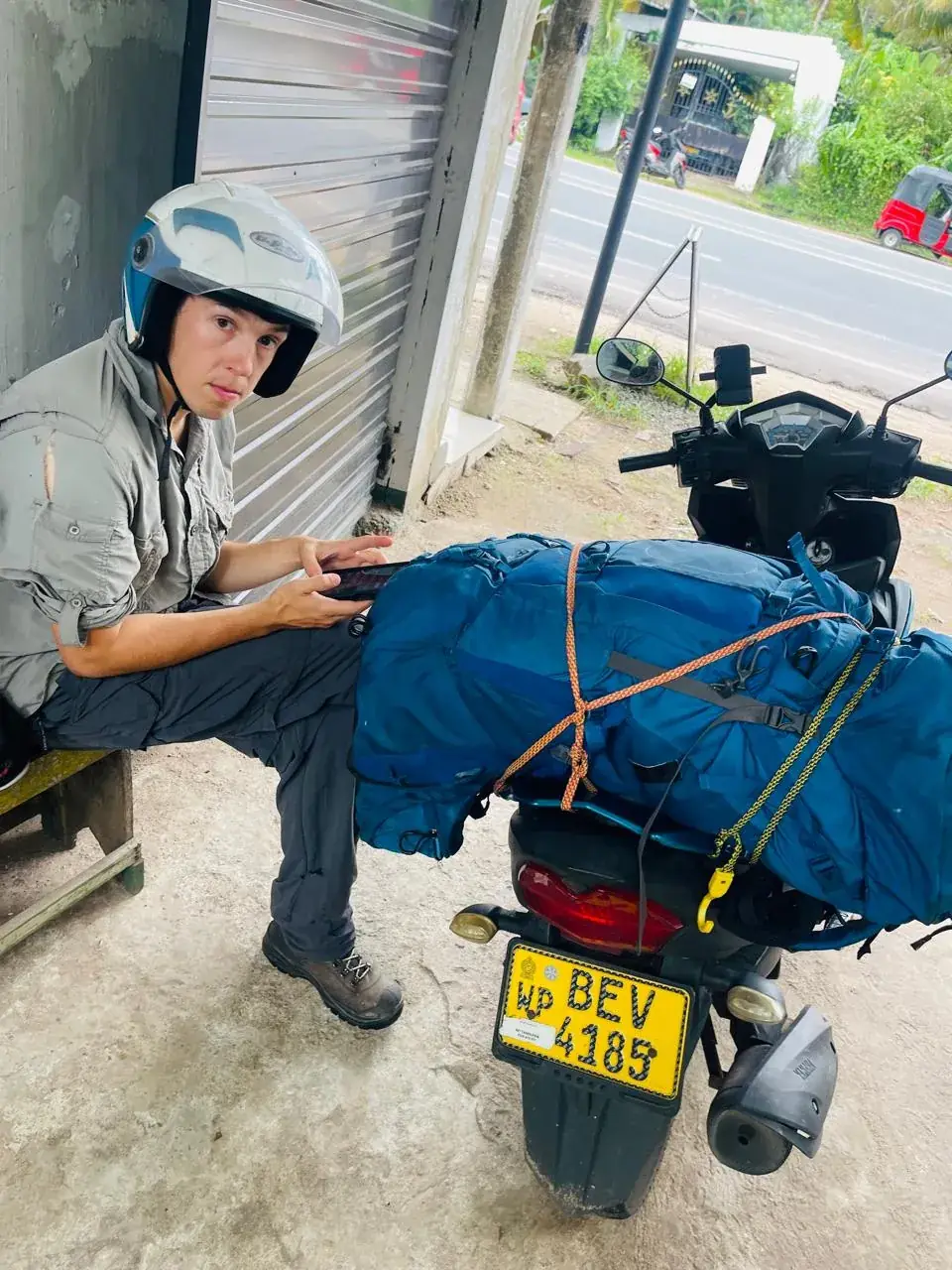 Traveller with backpacks strapped to a CeylonGo scooter before departure